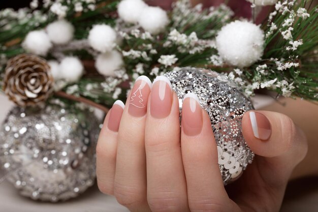 Manucure Blanche-Neige sur les mains féminines. Conception d'ongles d'hiver. Photo prise en studio sur fond de laine.