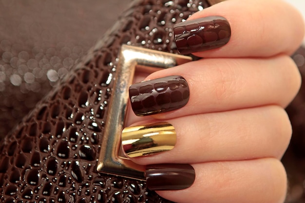 Manucure brune avec vernis à ongles doré