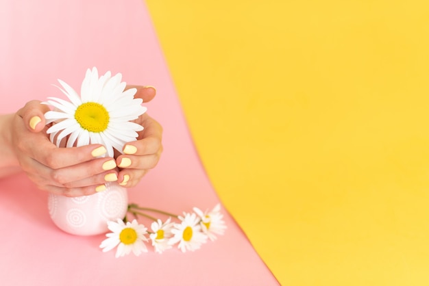 Manucure femme tendance élégante, les mains de la belle jeune femme sur fond rose et bleu.