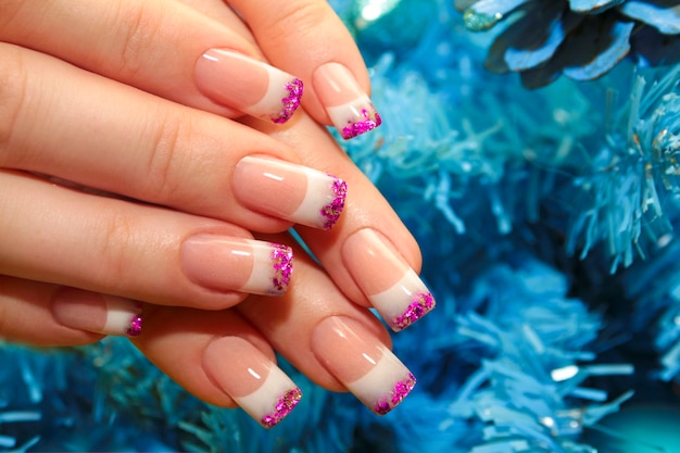 Manucure française de conception d'hiver de Noël avec des paillettes roses au bout des ongles.