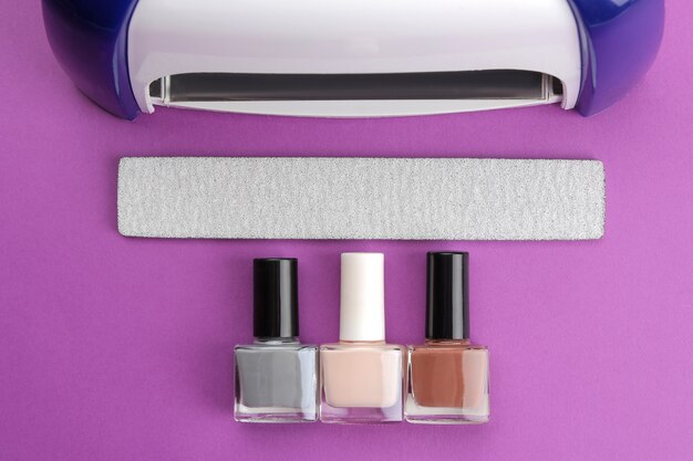 Manucure. Lampe UV et limes à ongles et vernis à ongles sur fond violet tendance. Accessoires et outils de manucure pour les ongles. vue de dessus