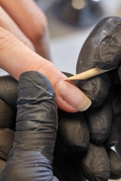 Manucure lime les ongles du client à table Retrait de la plaque à ongles avec une fraiseuse soin des ongles