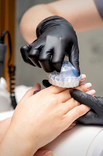 Manucure Master brosse la poussière des ongles féminins dans un salon de manucure