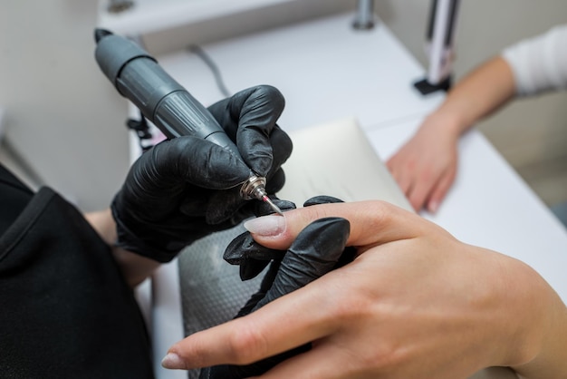 Manucure matérielle professionnelle sur une machine électrique dans un salon de manucure Le processus de levage de la cuticule avec un gros plan de coupe Master utilise une perceuse à lime à ongles électrique pour couper et enlever les cuticules