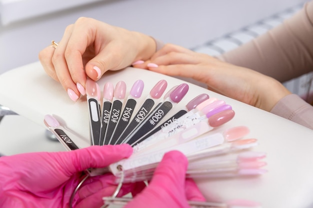 Manucure professionnelle montrant un vernis à ongles coloré pour vérifier le résultat final