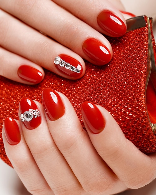 Photo manucure rouge festive lumineuse sur les mains féminines