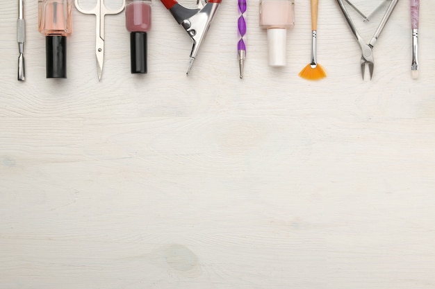 Manucure. vernis à ongles et divers accessoires et outils de manucure sur une table en bois blanc. vue de dessus