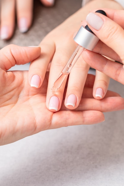 Manucure verse de l'huile sur les ongles d'une femme