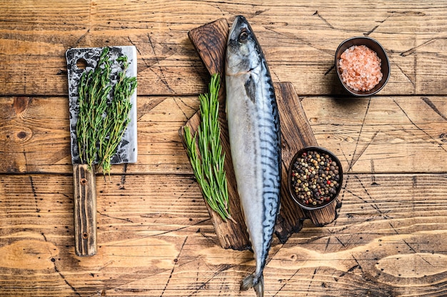 Maquereau de poisson d'eau salée cru sur une planche à découper en bois avec un thym. fond en bois. Vue de dessus.