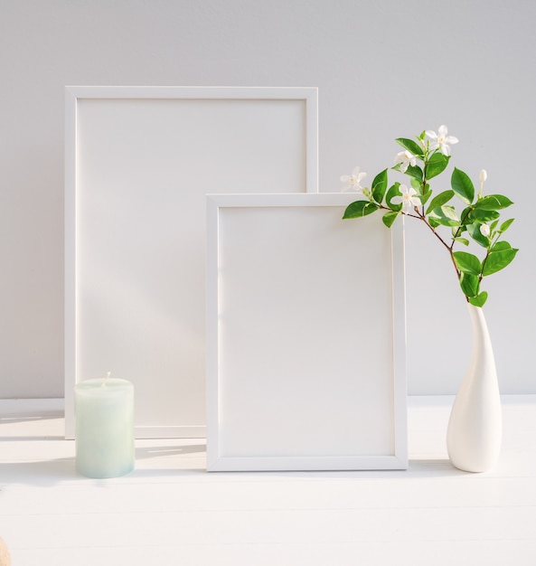 Maquette affiche cadre blanc et beau jardin tropical floral dans un décor de vase blanc moderne avec une bougie verte sur une table beige et une surface de mur de ciment à grandissime