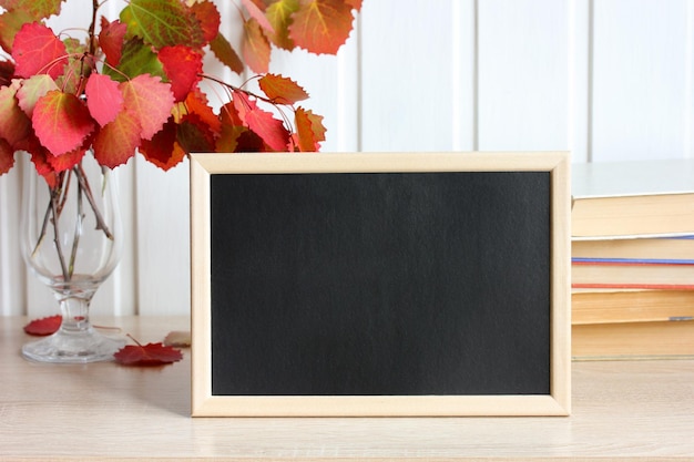 Maquette d'automne avec des feuilles de tremble rouge et un cadre vide avec un fond noir Retour au fond de l'école