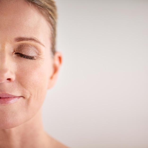 Maquette de beauté et demi-visage avec une femme en studio sur fond gris pour la publicité de soins cosmétiques Bien-être du visage et yeux fermés avec un modèle féminin senior posant pour des soins naturels de la peau