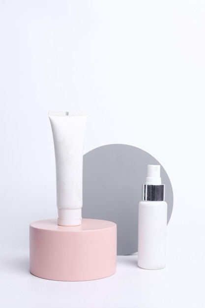 Maquette de beauté sur podium rose. Tube blanc et vaporisateur sur podium rose