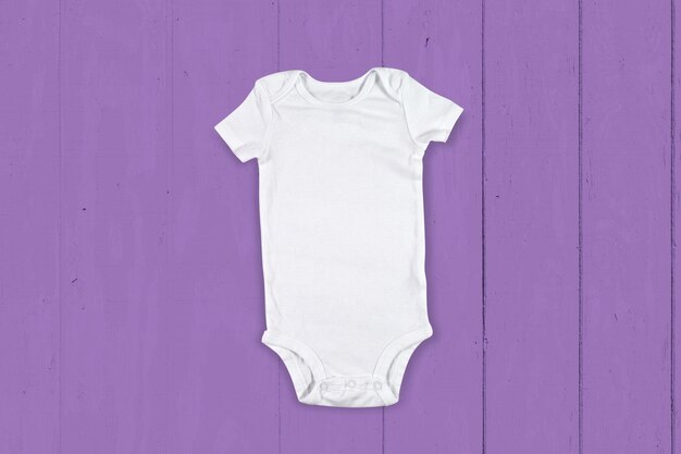 Photo maquette de body bébé sur fond de bois violet moderne