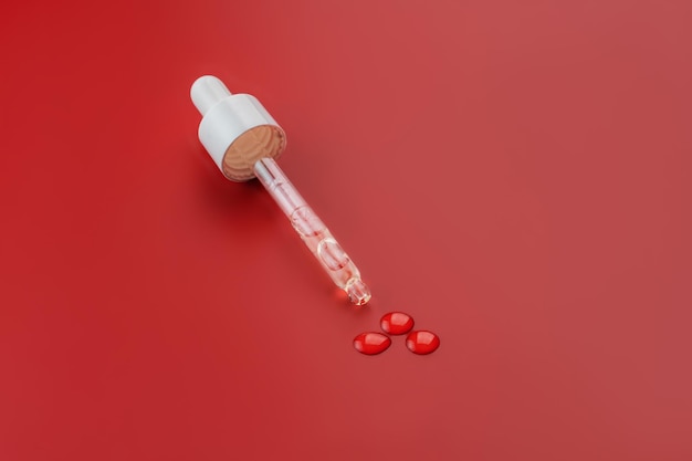 Maquette de bouchon de bouteille en verre à goutte-à-goutte Pipette cosmétique à fond rouge Concept de cosmétiques anti-âge et de beauté Minimalisme soin de la peau