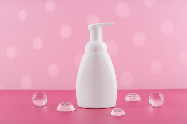 Maquette de bouteille cosmétique blanche de savon de bain sur fond rose avec des accessoires élégants Produit de mousse de soin du corps ou emballage de lotion Tube de cosmétiques en plastique vue de face maquette Crème pour le corps