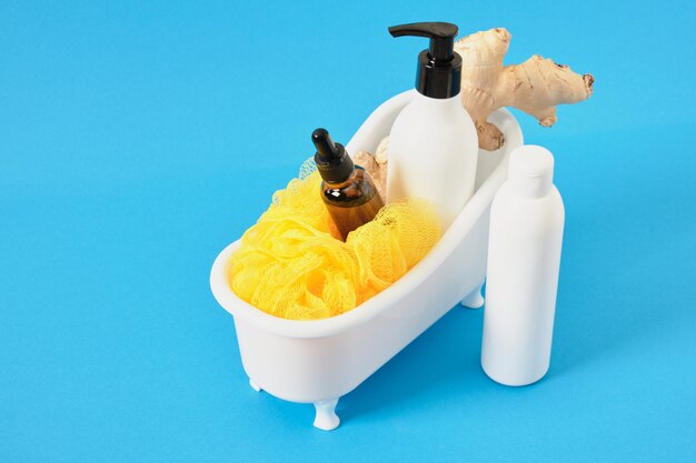 Maquette d'une bouteille avec un distributeur et une pipette pour l'huile ou la crème un gant de toilette et une racine de gingembre dans un bain miniature
