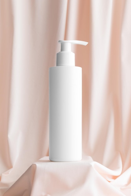 Maquette de bouteille de distributeur de shampoing cosmétique blanc sur le textile rose tendre