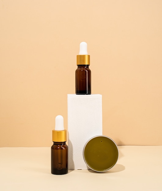 Maquette de bouteilles brunes pour accessoires de spa cosmétiques de soins de la peau naturels sur fond crème de podiums blancs
