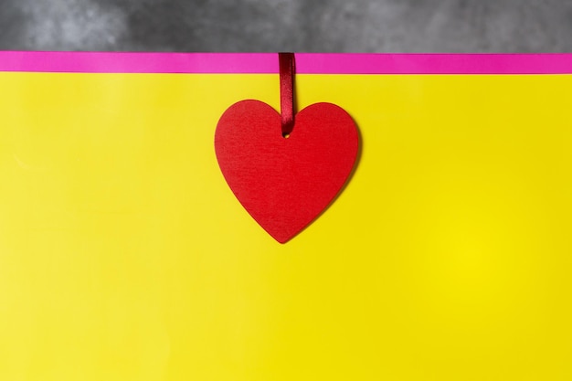 Photo maquette de cadeau de saint valentin dans des couleurs vives rose et jaune avec une étiquette en forme de coeur rouge