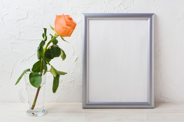 Maquette de cadre en argent avec rose orange-abricot dans un vase en verre