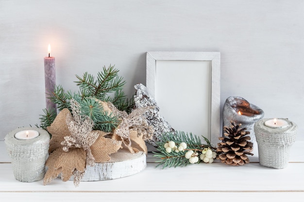 Maquette de cadre blanc de décoration de Noël avec un bouquet de bougie de sapin sur une table blanche