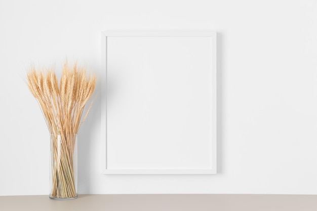 Maquette de cadre blanc sur le mur avec une décoration de fleurs séchées