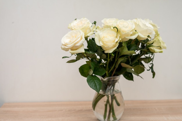 Maquette de cadre blanc portrait sur table en bois. Vase moderne avec des roses. Intérieur scandinave. photo de haute qualité