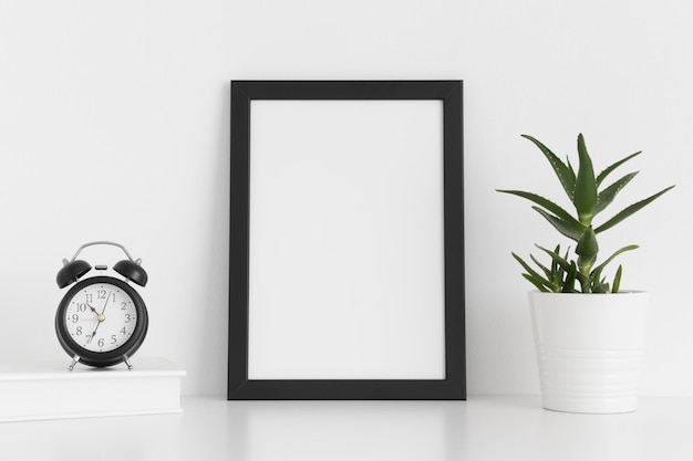 Maquette de cadre noir avec accessoires d'espace de travail et aloe vera sur une table blancheOrientation portrait
