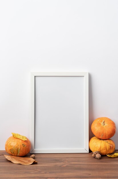 Maquette de cadre photo d'art avec des écharpes et des feuilles d'automne fond blanc