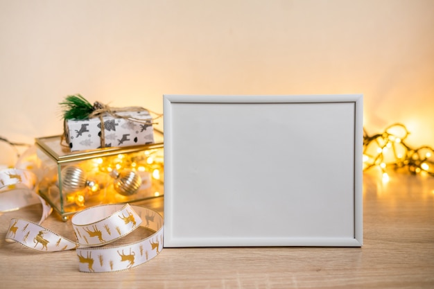 Maquette de cadre photo blanc portrait avec cadeaux de Noël, lumières boken. photo de haute qualité