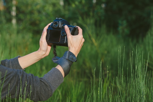 Maquette d'une caméra photo-vidéo professionnelle entre les mains d'une fille. Dans le contexte de la nature verte.