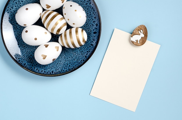 Maquette de carte Joyeuses Pâques sur fond bleu avec des oeufs sur un plat bleu foncé