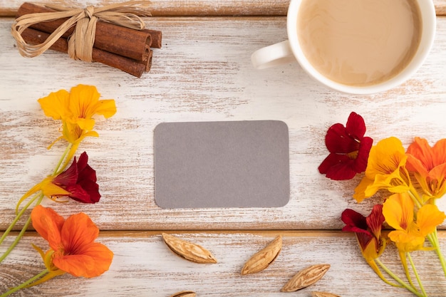 Maquette de carte de visite en papier gris avec fleur de capucine orange et tasse de café sur fond en bois blanc vue de dessus copie espace