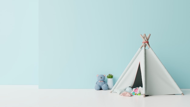 Maquette dans la salle de jeux pour enfants avec une poupée assise sur une tente et une table sur un mur bleu vide.