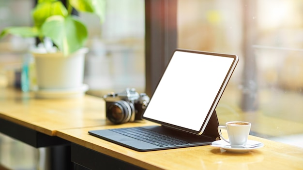 Maquette d'écran blanc d'ordinateur tablette numérique moderne avec support de clavier sur table en bois