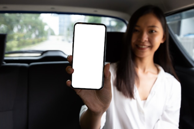 Maquette d'une femme asiatique tenant un téléphone portable alors qu'elle était assise sur le siège arrière de la voiture