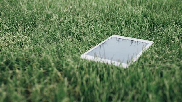 Maquette image de tablet pc allongé sur l'herbe