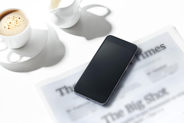 Photo maquette d'image d'un téléphone mobile avec un écran vide et une tasse de café latte art sur une table dans un café.