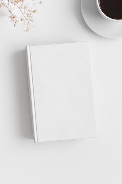 Maquette de livre blanc avec une tasse de café et de gypsophile sur un tableau blanc