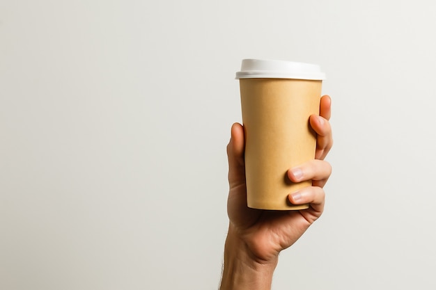 Maquette de main masculine tenant une tasse de papier café isolée sur fond gris clair