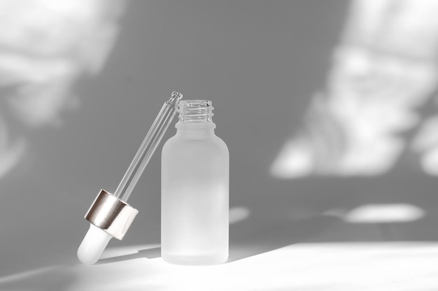 Maquette de marque cosmétique Flacon cosmétique blanc avec huile essentielle et pipette sur fond blanc avec ombres Concept de soins de la peau