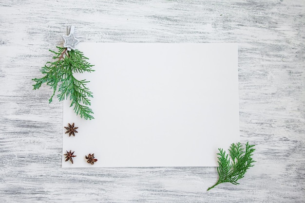 Photo maquette de noël avec des branches de pin sur du papier blanc