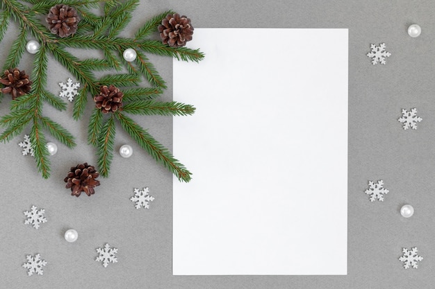 Maquette de Noël avec des branches de sapin, des cônes et des flocons de neige argentés. Espace pour le texte.