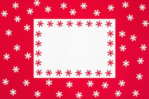 Maquette de Noël avec des flocons de neige sur fond rouge. Espace pour le texte.