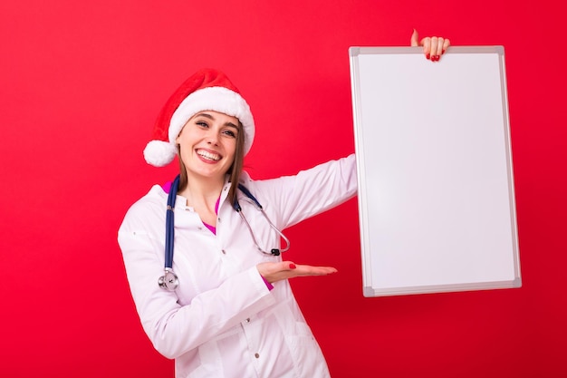 Maquette de Noël Une infirmière dans un bonnet de Noel tient une affiche blanche sur fond rouge