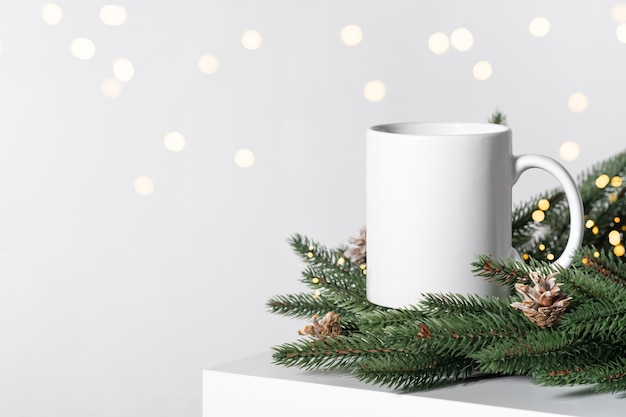 Maquette de Noël une tasse de thé vide blanche sur une table blanche et des branches d'une couronne d'arbre de Noël.