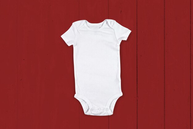 Maquette de Onesie bébé blanc sur fond de bois rouge rustique
