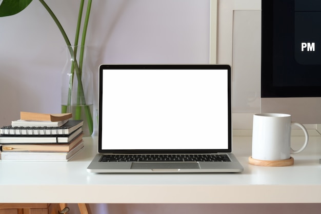 Maquette ordinateur portable à écran blanc sur un espace de travail blanc