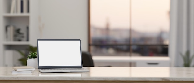 Maquette d'ordinateur portable et espace de copie sur une table blanche moderne sur un bureau flou en arrière-plan